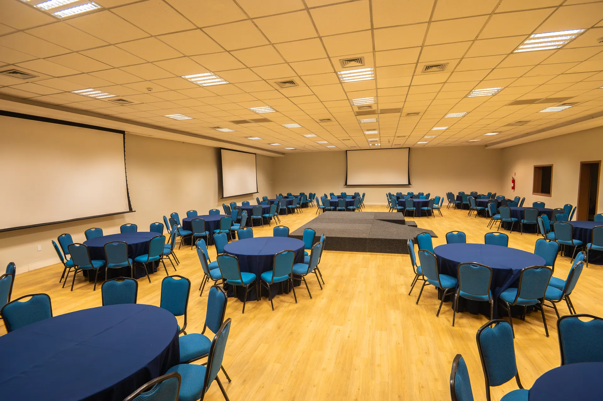 Salão Jatiúca montado com mesas redondas e palco, no maior espaço do Centro de Eventos