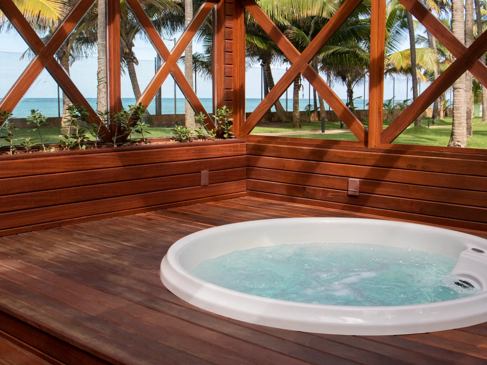 Hidromassagem do Spa do Jatiúca em deck de madeira, sob o coqueiral